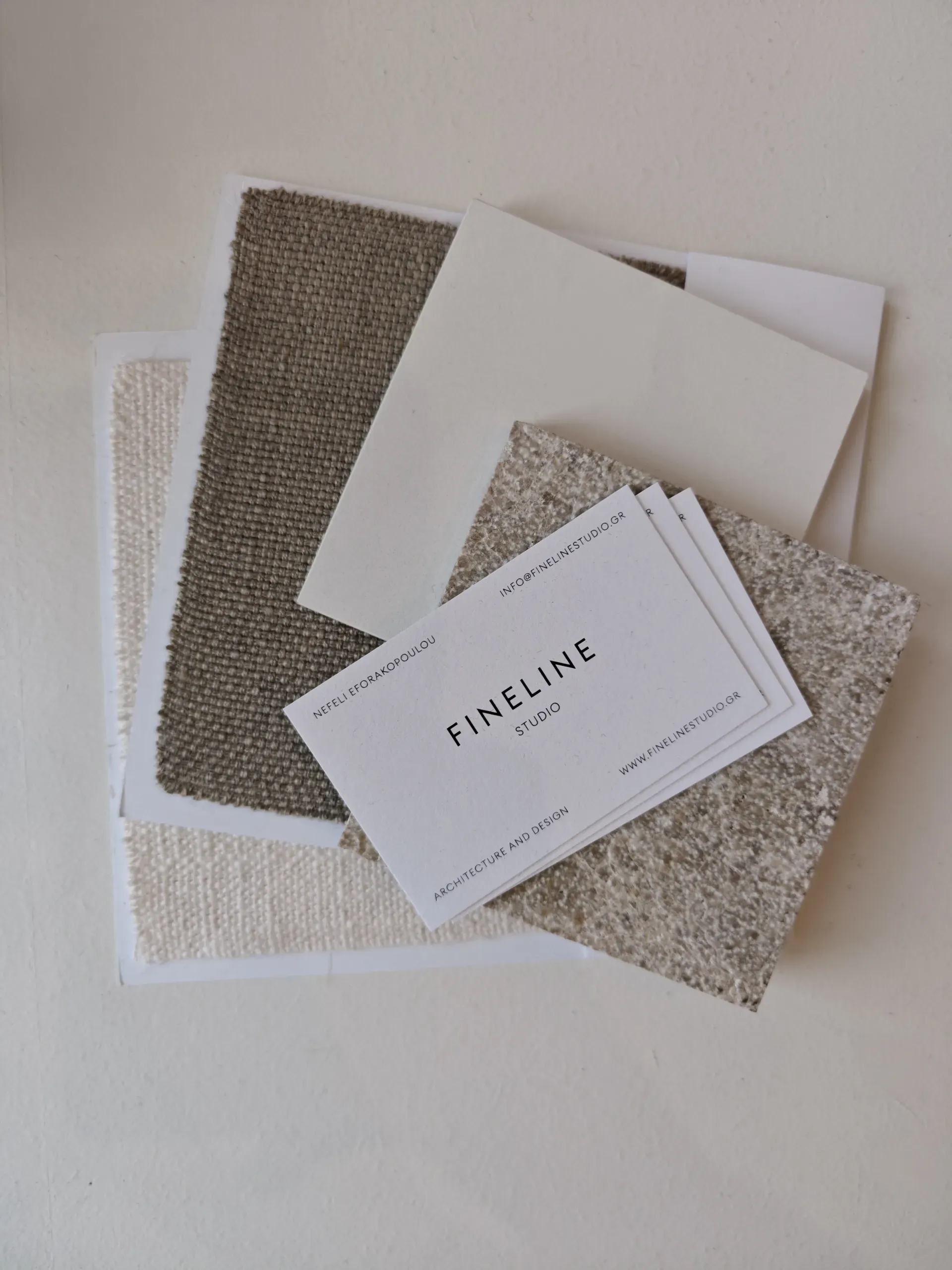 Fineline Studio business cards arranged over neutral textile samples